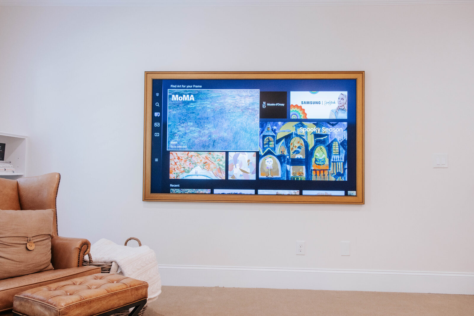 A very large piture-framed TV screen hanging on a wall, with it turned on and displaying menu content.